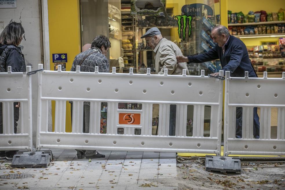 Varios viandantes ayudan a una persona mayor a salvar un obstáculo en uno de los 'pasillos'. / JUSTO RODRÍGUEZ