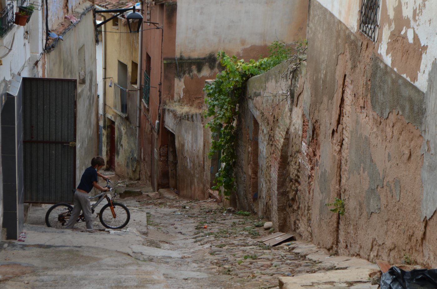 Un niño sale de casa con su bicicleta por el rudimentario pavimento de la Cuesta de la Curruca. / I.Á.