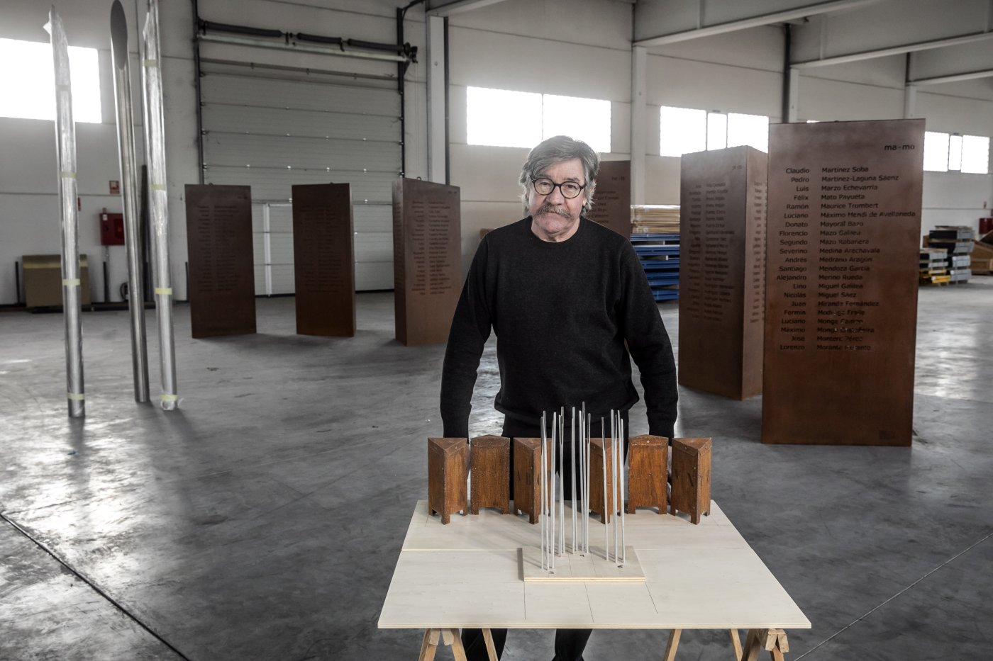 Óscar Cenzano posa juntoa la maqueta del memorialdelante de los elementosdel mismo a la espera de su instalación