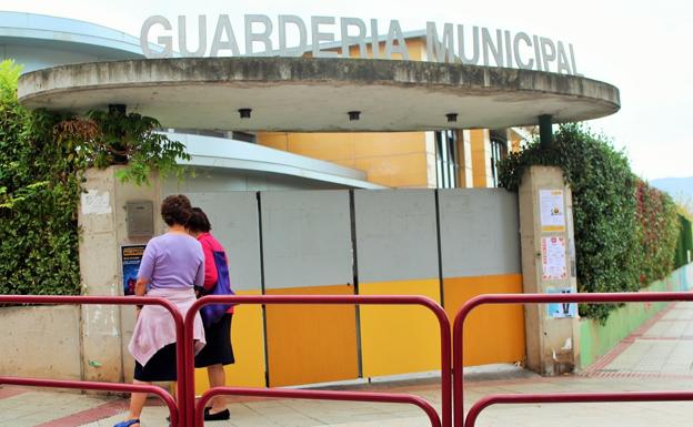 Dos mujeres observan un cartel colgado en la puerta de la guardería municipal de Villamediana de Iregua. / D.M.A.