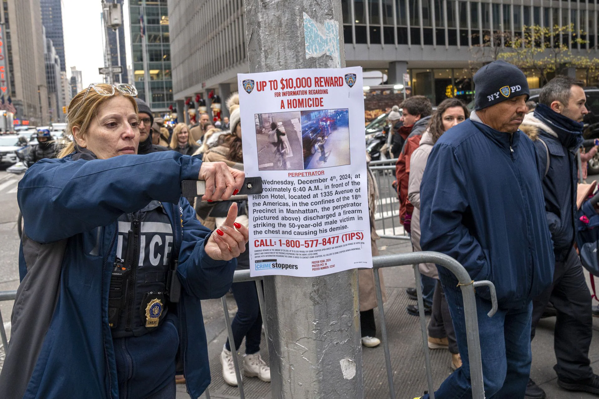 El miedo atenaza a los ejecutivos de Nueva York. En la image, una agente coloca un cartel con las fotografías del asesino el consejero delegado de una gran aseguradora médica.