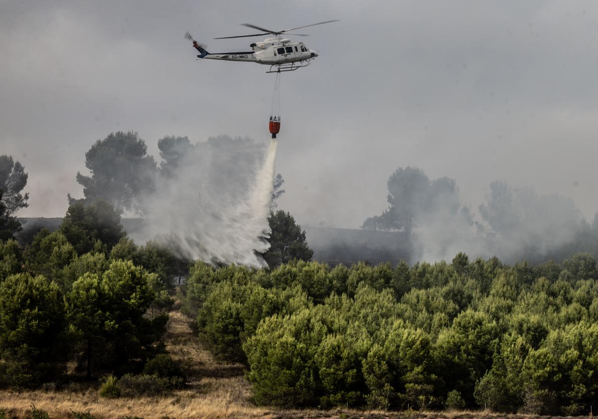 El helicóptero vierte el agua sobre la zona forestal afectada por el incendio del Ecoparque.